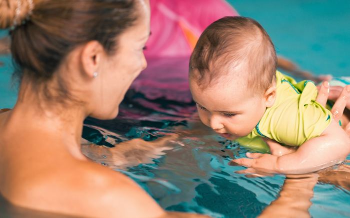A baby held in the water by a parent during a lesson