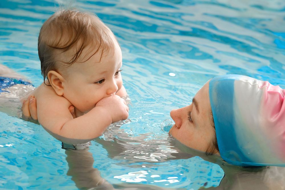 A baby supported in the water by a parent