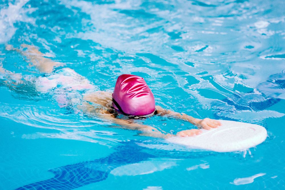A young swimmer practising with a kickboard