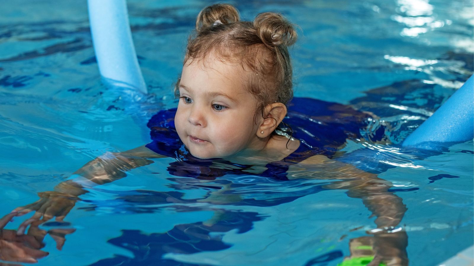 A toddler moving through the water with a float